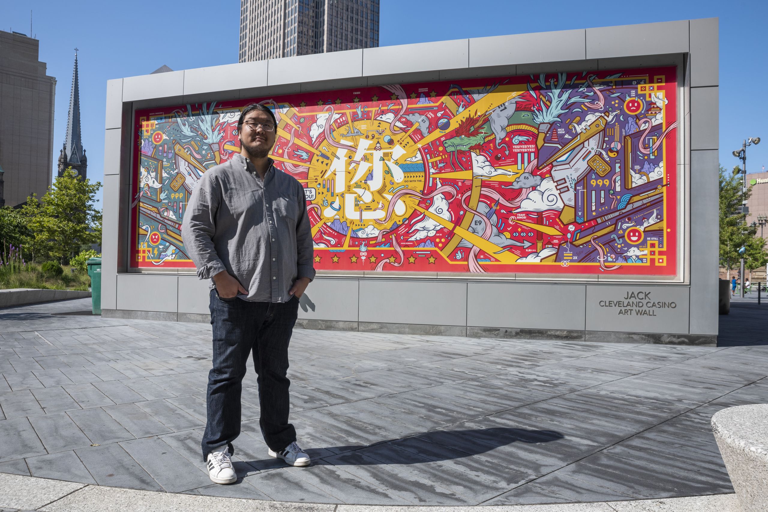 Jordan Wong stands in front of his mural, "Triumph of Heaven, Earth, and the Cosmos", which debuted on Public Square and will be moved to Asia Plaza.
