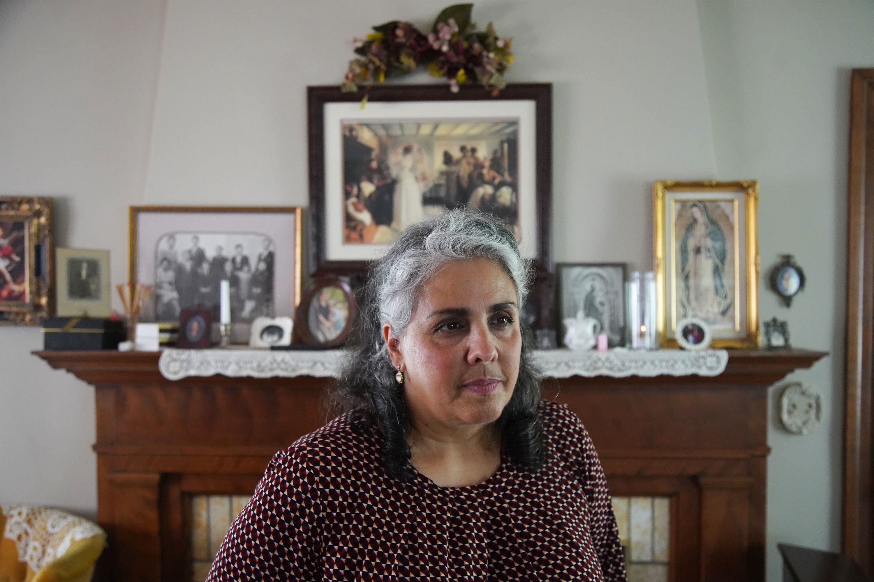 Rita Vitale stands in her living room in front of her fireplace mantle..