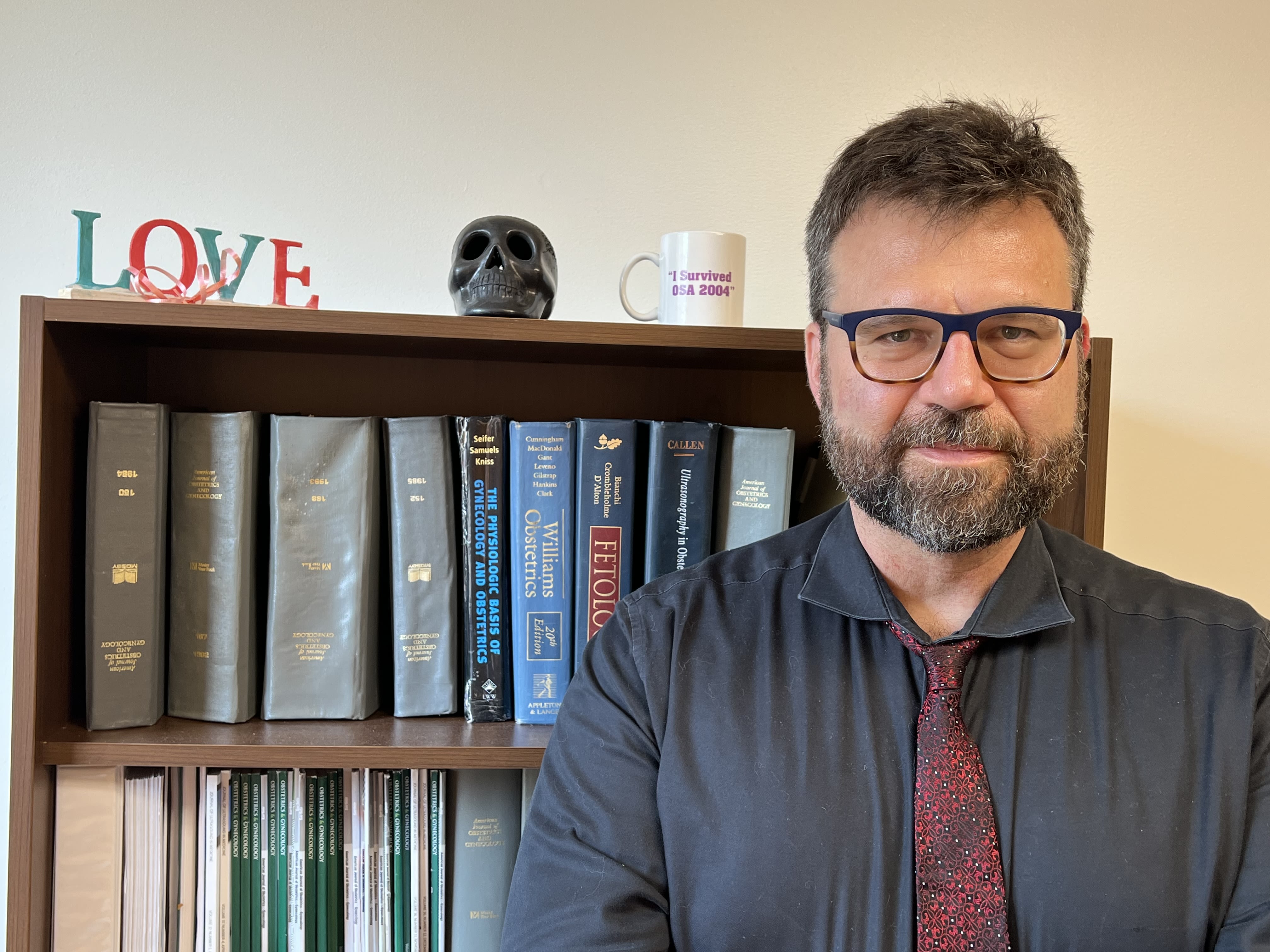 Dr. David Hackney stands in front of a bookshelf.