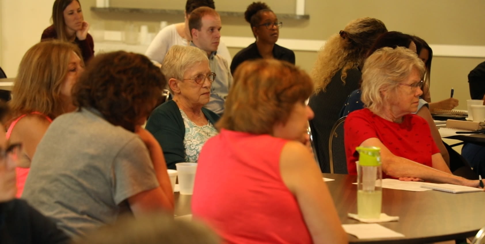 Photo of Cheryl Throop sitting at a table with four other women listens as suicidologist Frank Campbell talks about strategies to help people considering suicide.