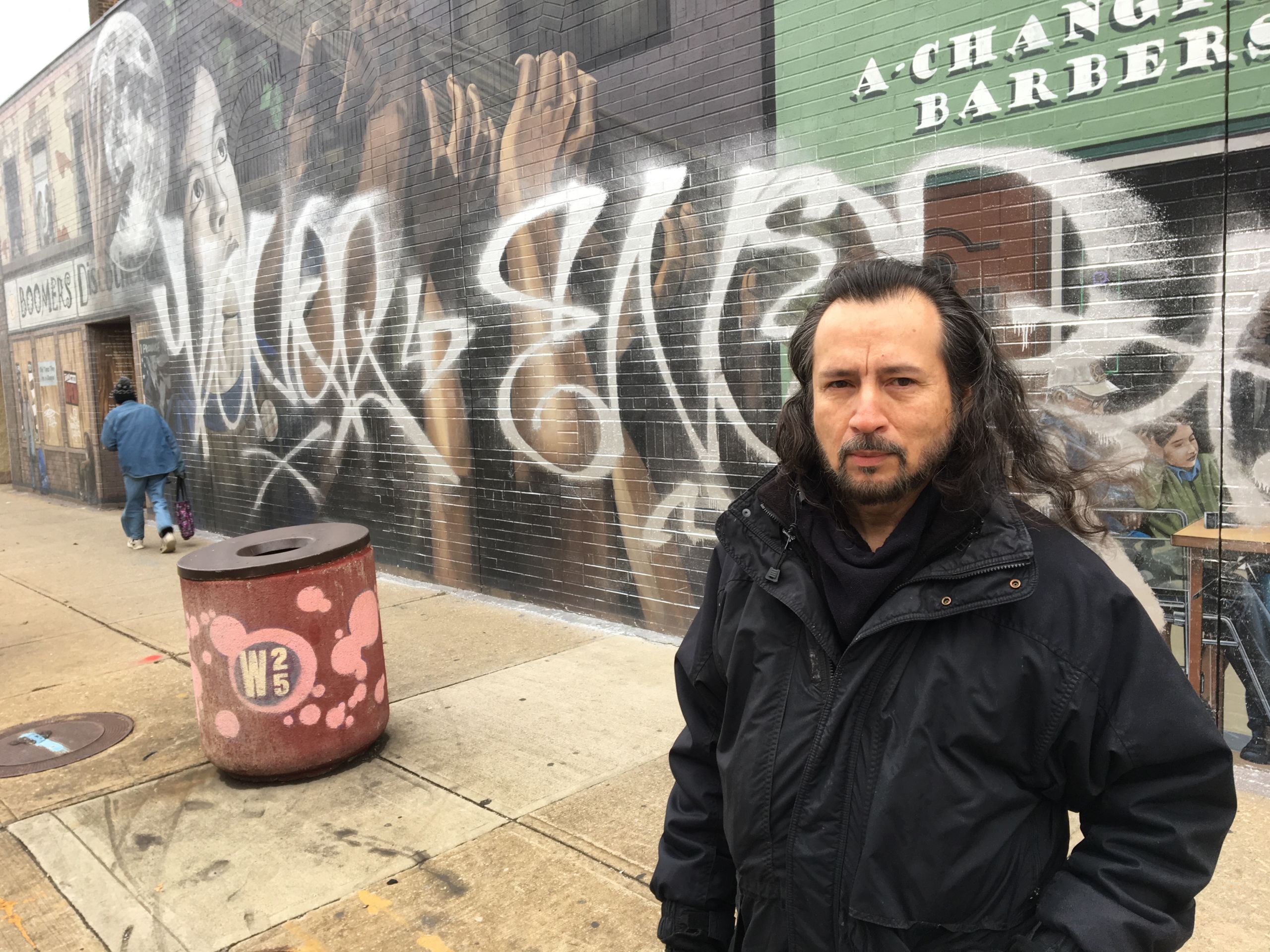 Rivera-Resto stands by his two-story mural "It's Up To Us" at W. 25th and Clark Avenue after it was defaced by a graffiti tagger.