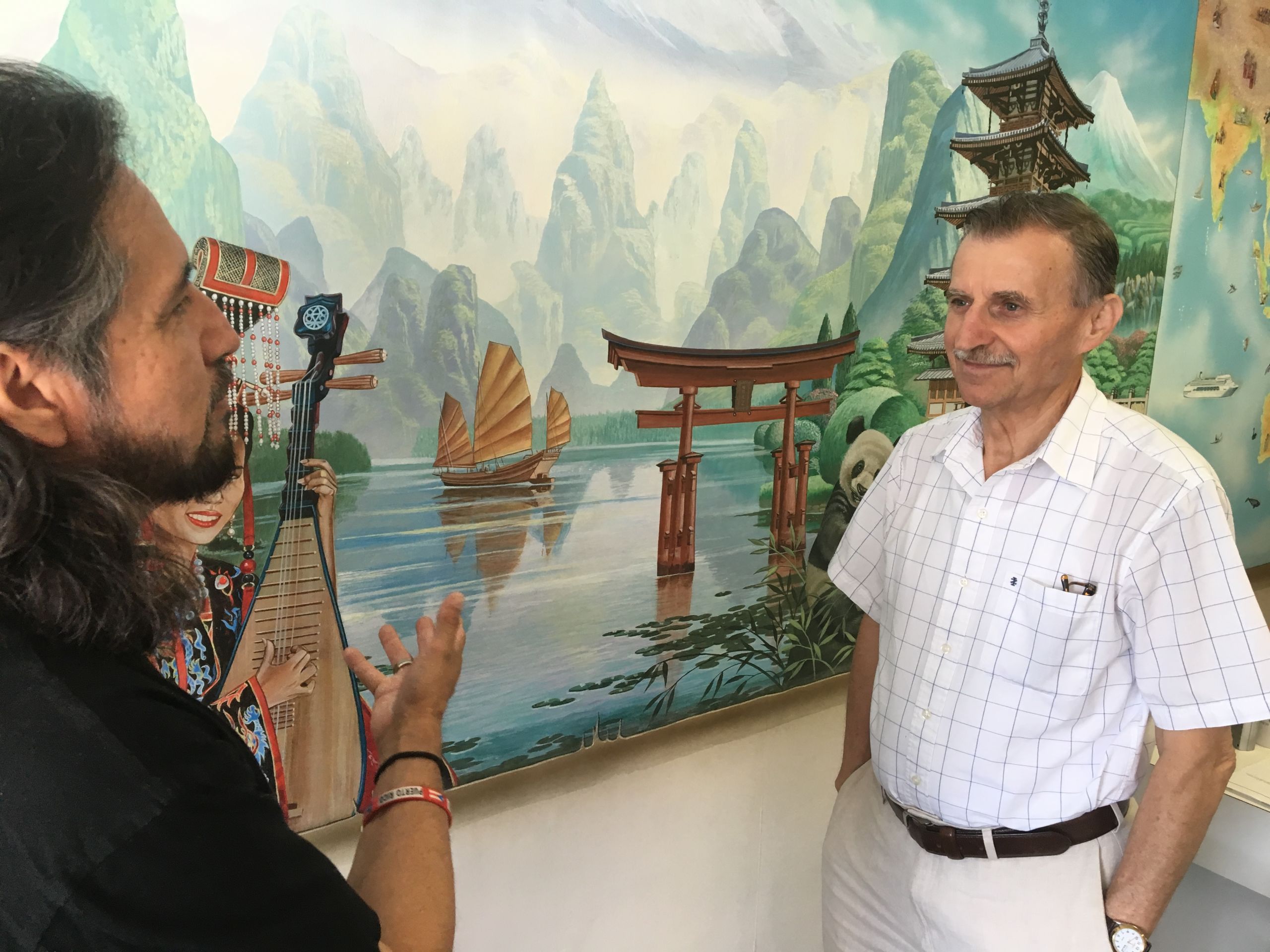 Rivera-Resto discusses his Asian-themed mural at Panorama Travel with owner Vladan Blogojevic.