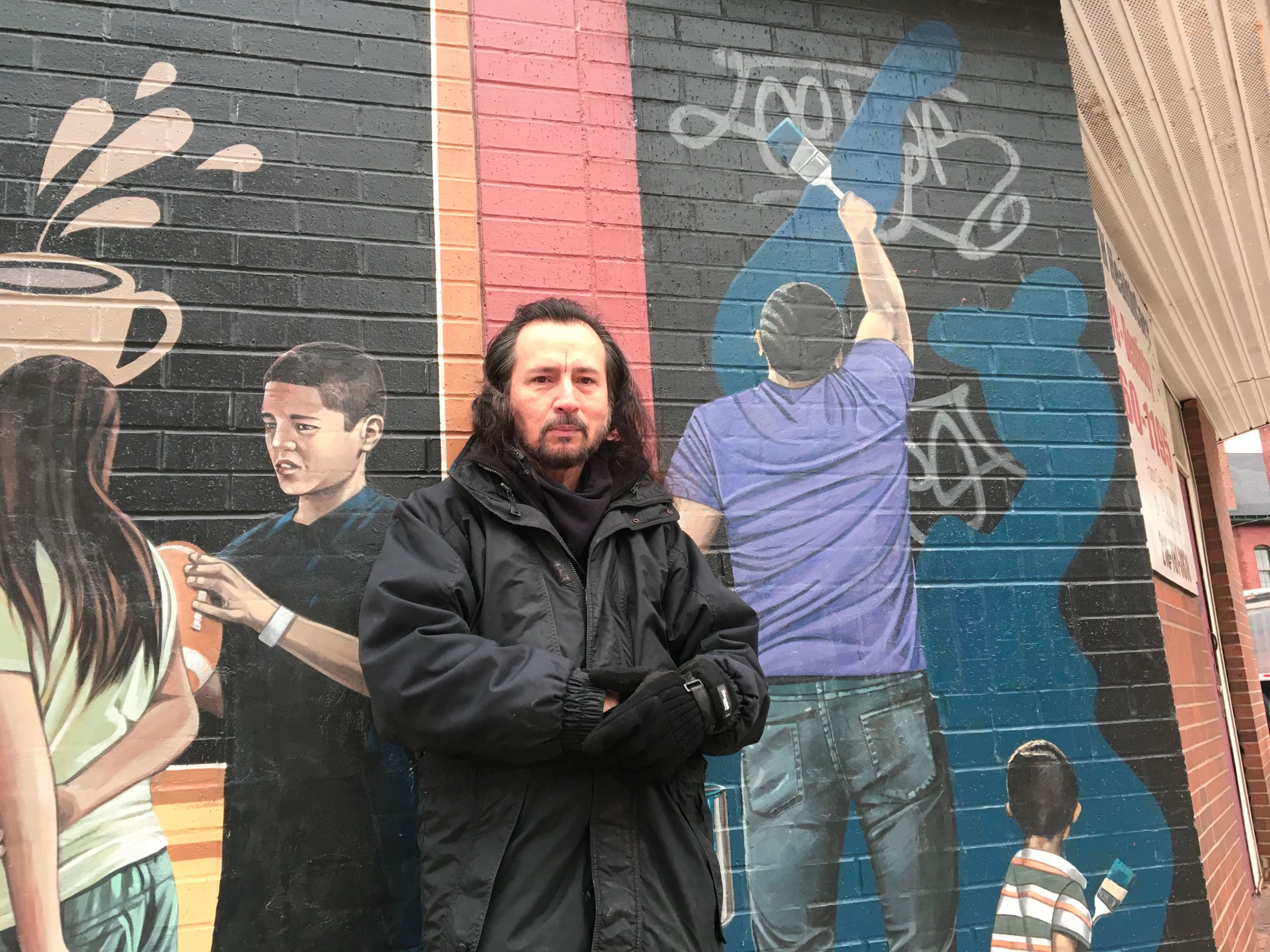 The artist poses by a segment of his mural that depicts the rehabilitation work he would actually have to do.